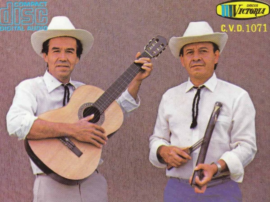 José Muñoz, prolífico compositor, guitarrista y cantante nacido en Bello, posando mientras toca un instrumento, interpretando música parrandera.