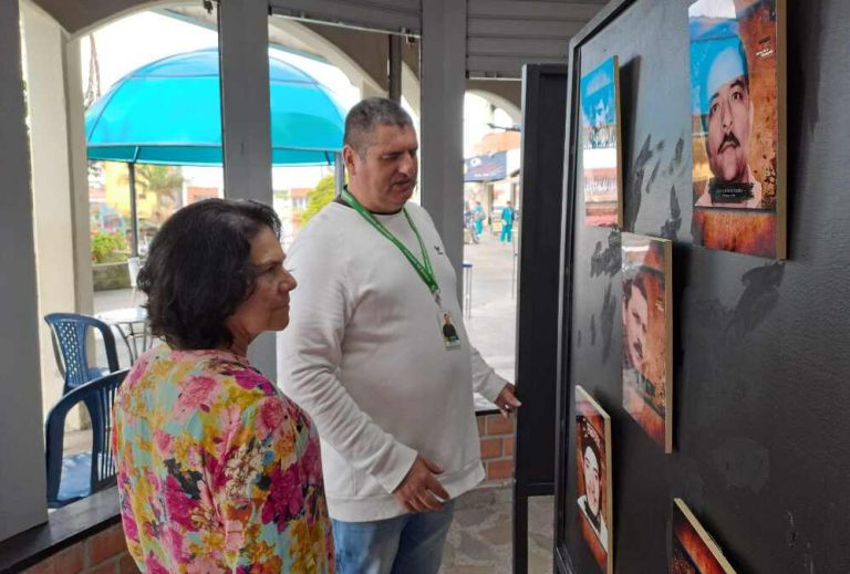 Un hombre y una mujer contemplan fotos y recuerdos relacionados con personas desaparecidas durante el conflicto armado en Guarne, Antioquia, en una muestra en el Museo Ra&iacute;ces de la Memoria.