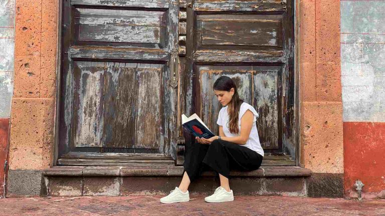 Alexandra Castrill&oacute;n, situada en la entrada de un edificio antiguo, est&aacute; sumida en la lectura de su novela Entre redes. Recientemente, lanz&oacute; su nuevo libro de cuentos titulado Unos minutos de amnesia, una obra de la escritora colombiana.